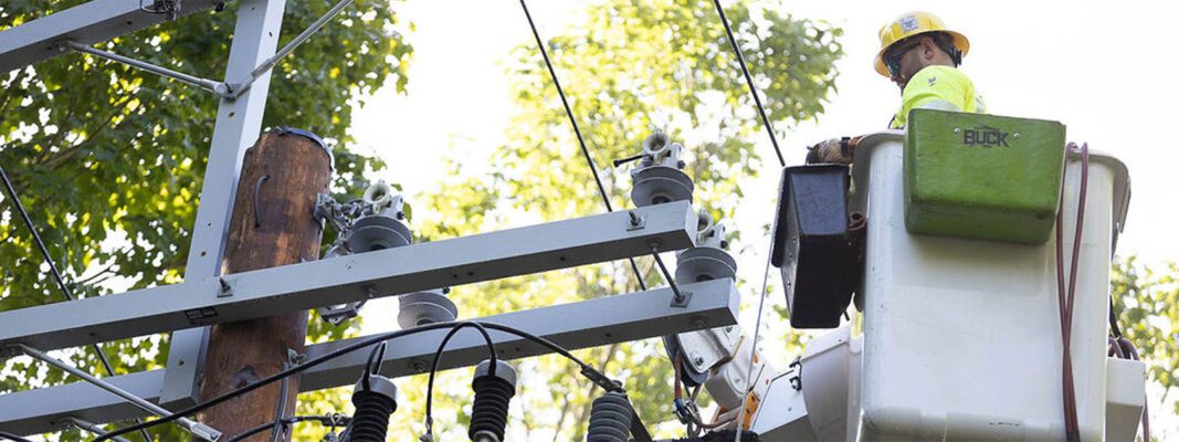 Lineman in bucket truck working near insulators on crossarm