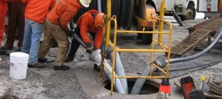 Linemen pulling conductor in a manhole