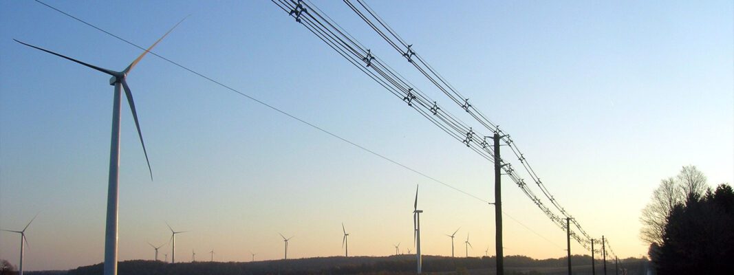 Solar spacer cableinstall with wind turbines in the background